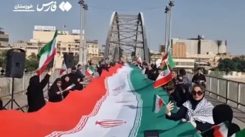 People stand on either side of the Iranian flag on the White Bridge in Ahvaz, Iran