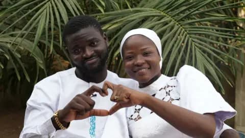 Olanrewaju and Kaosara next to each other using their hands to form a shape of a heart
