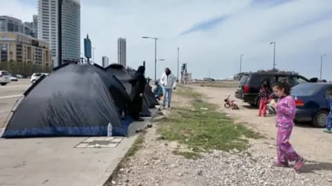 A pair of tents next to cars, a young girl wearing pink ice n the foreground