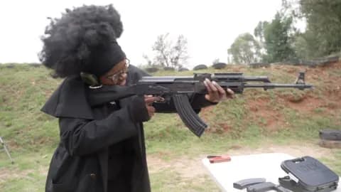 Woman dressed in black holding gun at a shooting range