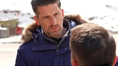 BBC correspondent Dan Johnson, wearing navy blue jacket, talking to a  man with a blur hiding his face.