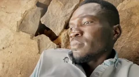 A man crouched in front of a wall