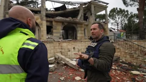 The BBC's Hugo Bachega (right) speaks to a paramedic amongst the ruins of an ambulance station in Lebanon