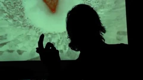 A silhouette of a man pointing his finger is seen in front of a light green background