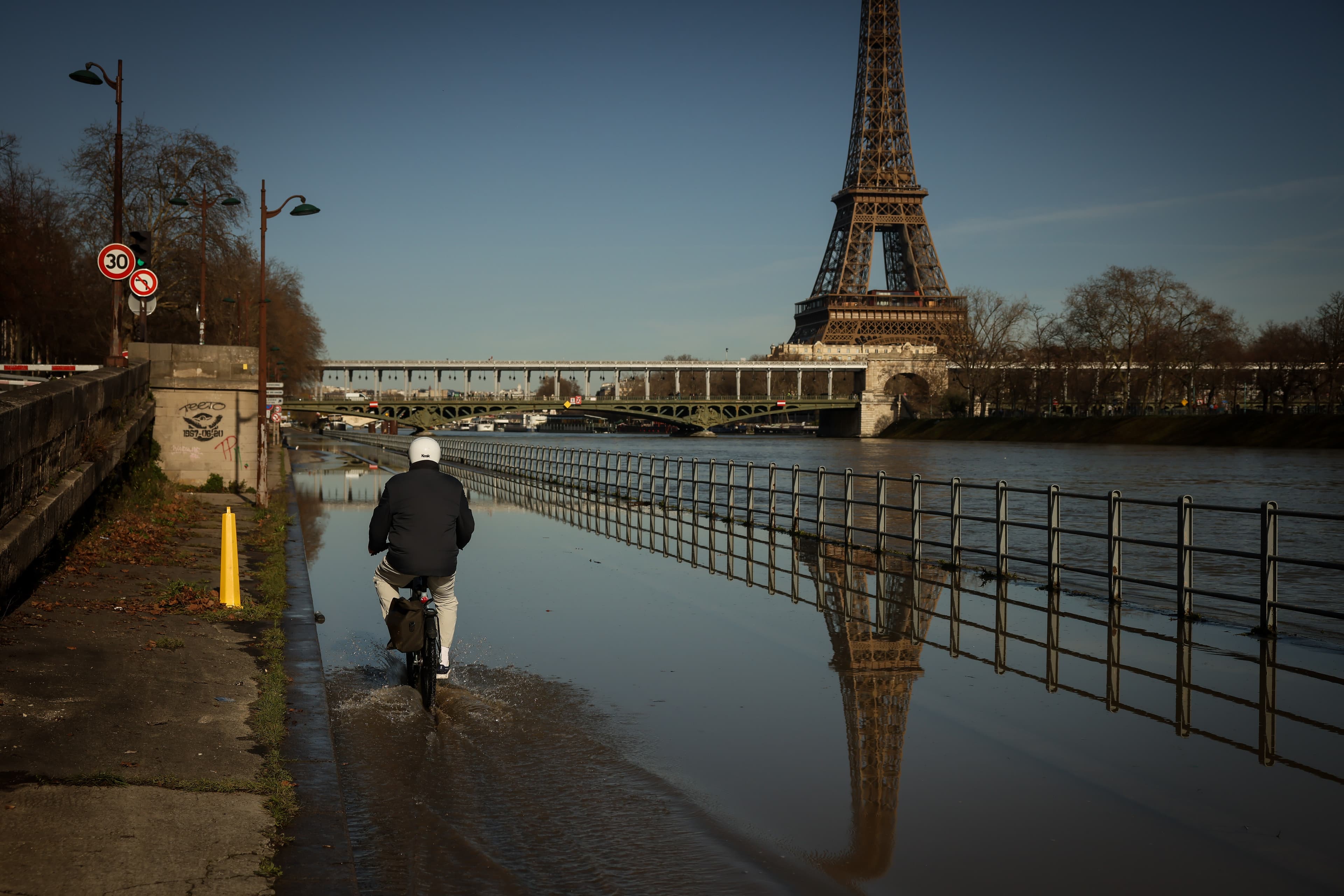 A man on a bicycle rides on the flooded banks of the Seine next to the Eiffel Tower in Paris on Feb. 25, 2026. 