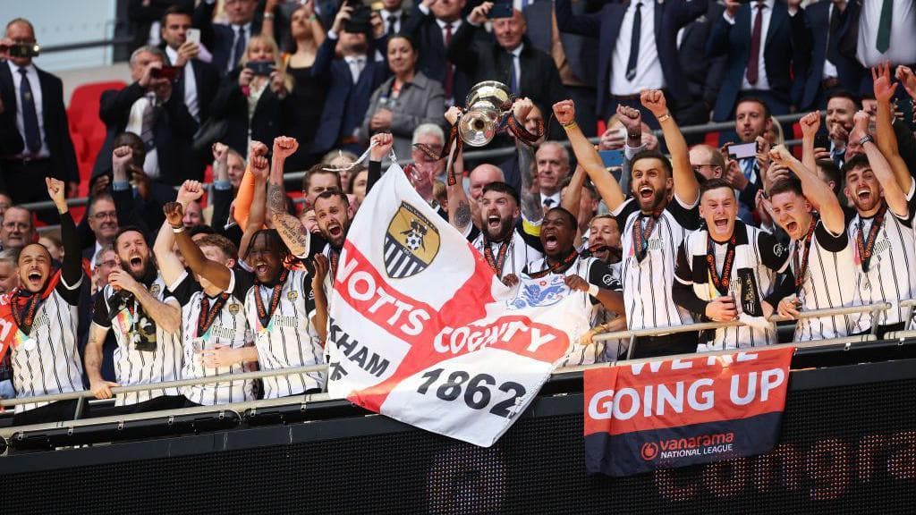 Notts County players look nervous while linking arms as they watch the penalty shootout from the halfway line during their victory over Chesterfield in the 2022-23 National League play-off final
