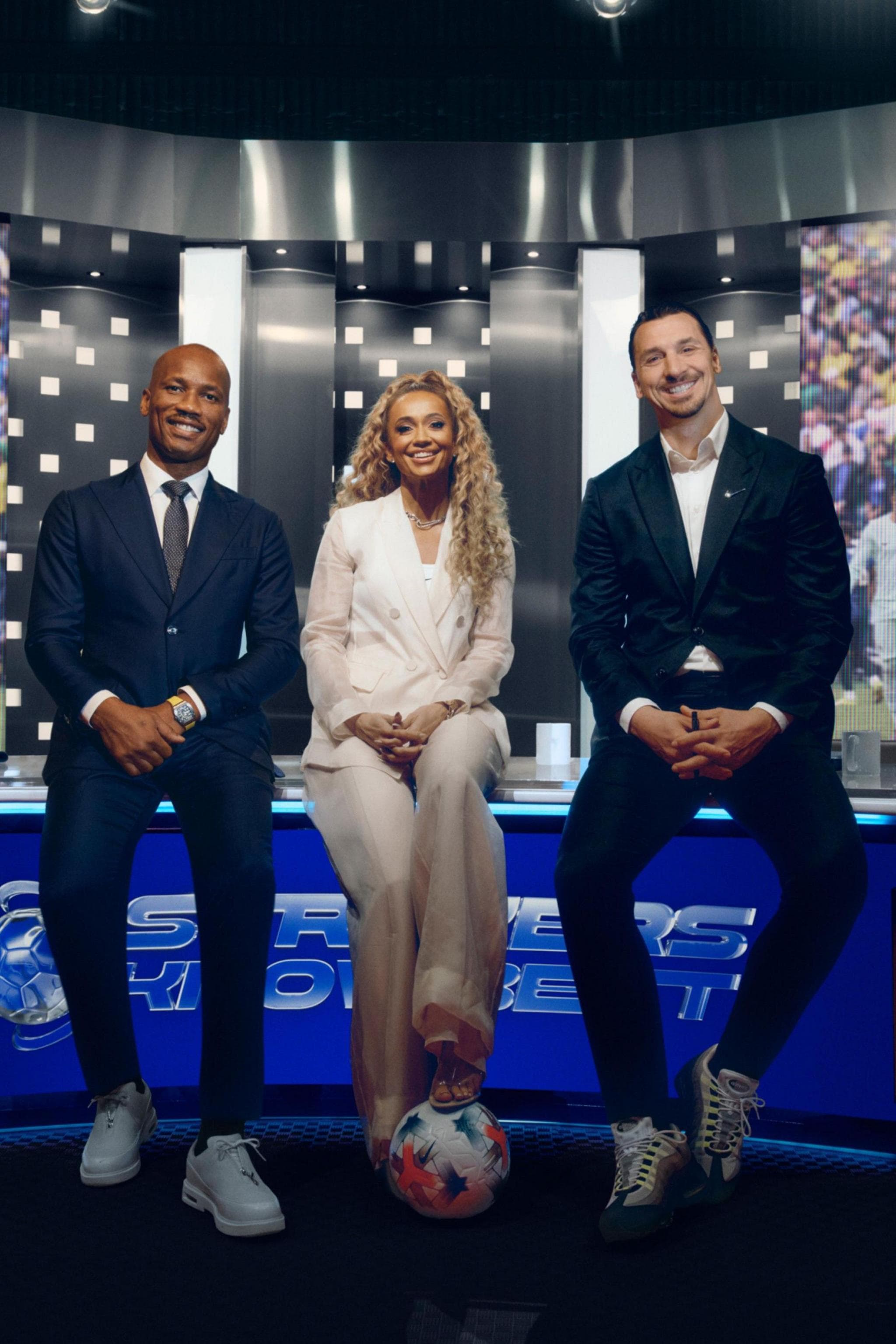 Didier Drogba, Kate Scott and Zlatan Ibrahimovic sitting on a studio desk in Nike's World Cup advert