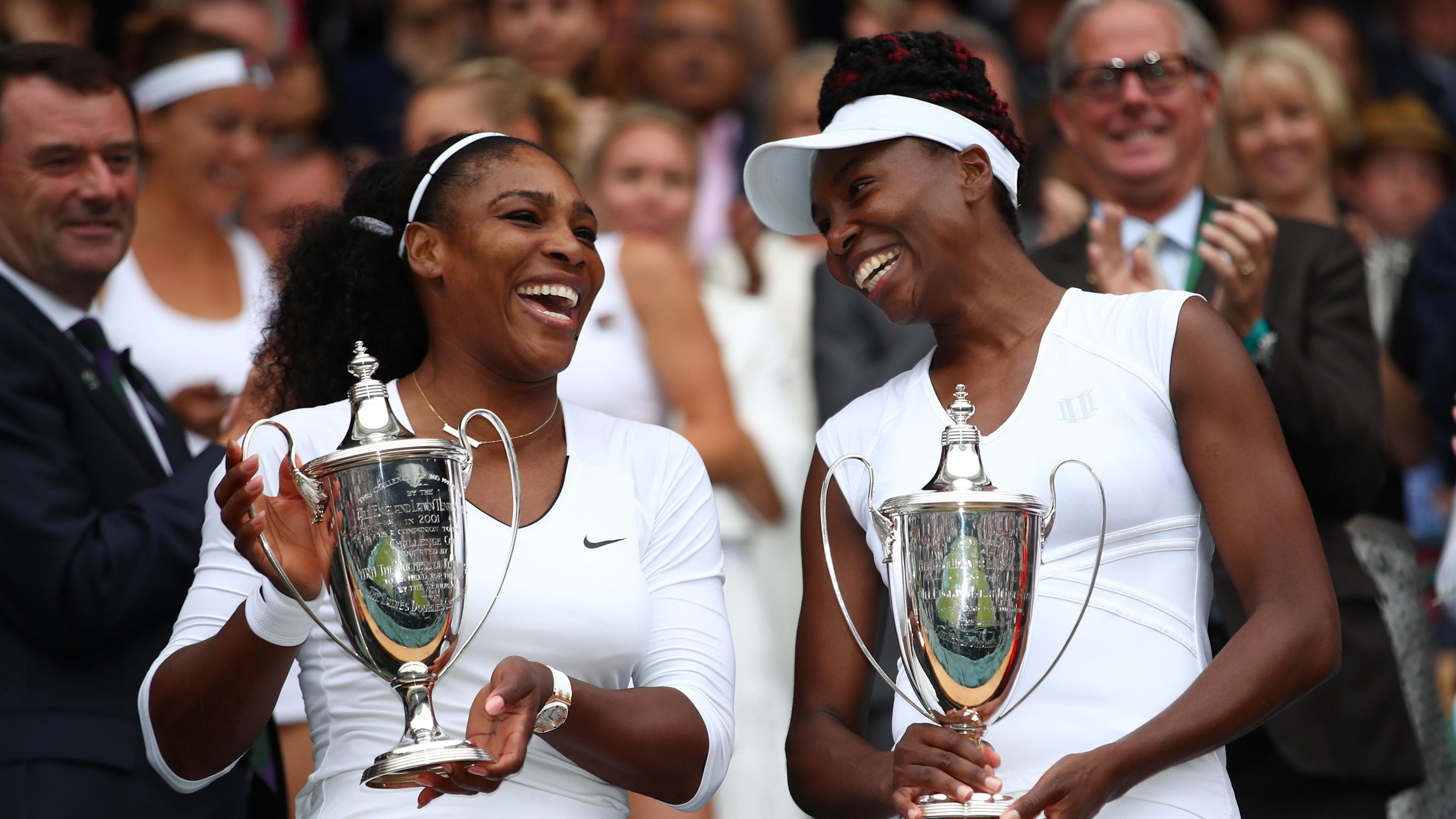 Serena and Venus Williams pose with the women's doubles trophies at Wimbledon in 2016