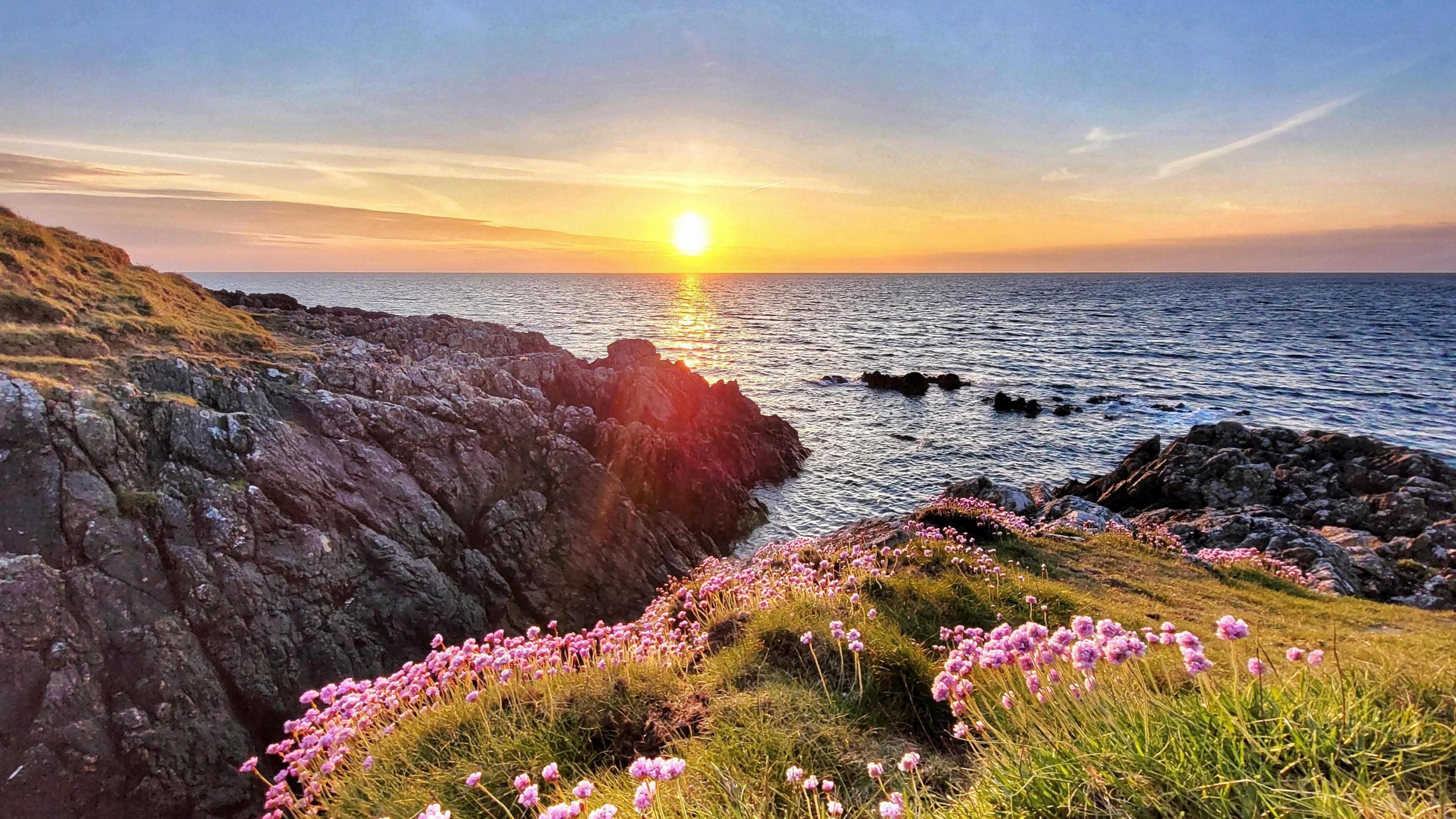 A rocky coastline with a setting sun in the background