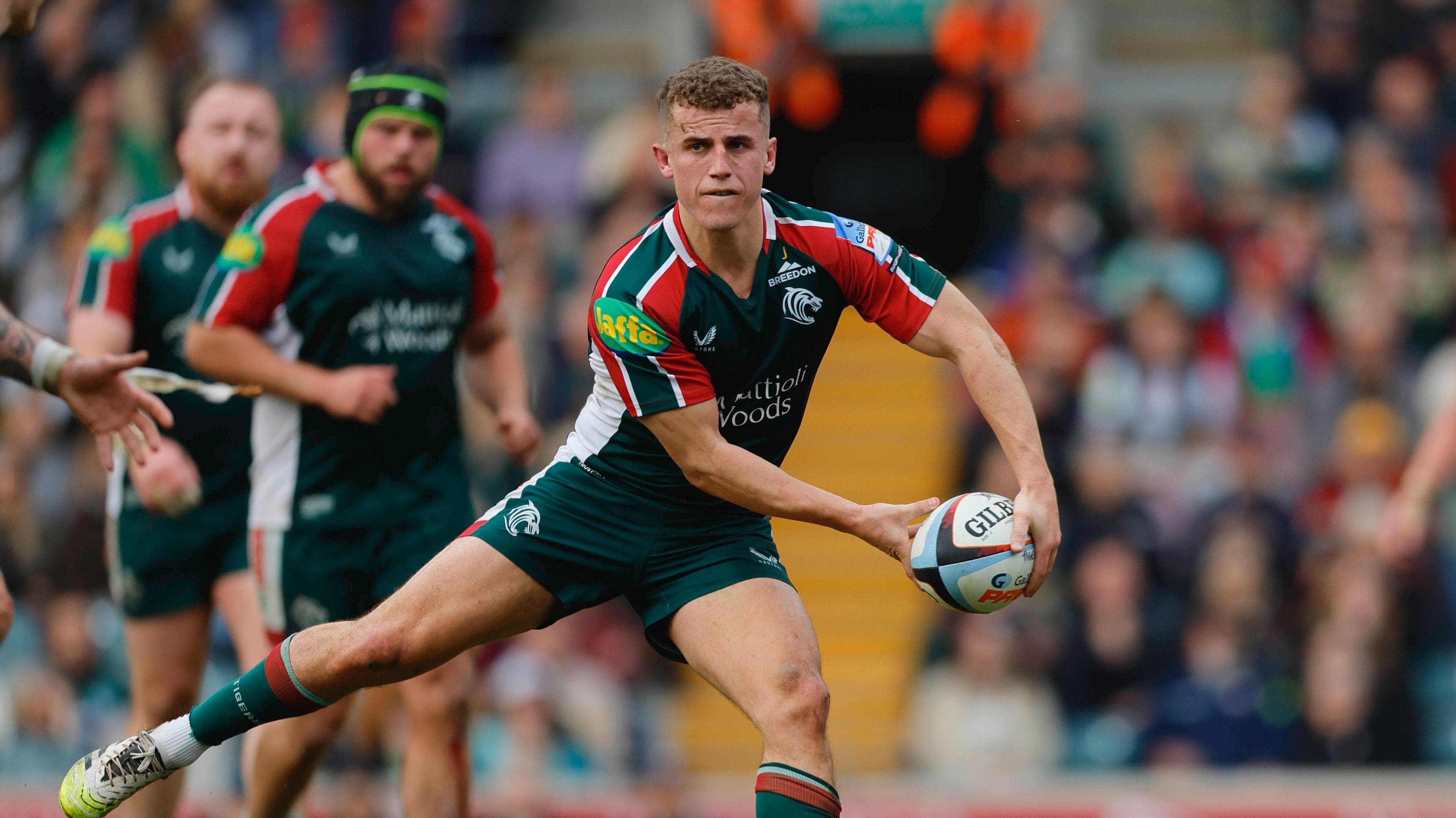 Billy Searle in action during a game with players and the crowd in the background.
