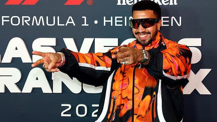 Miles Chamley-Watson wearing sunglasses and a brigh orange jacket at an F1 event