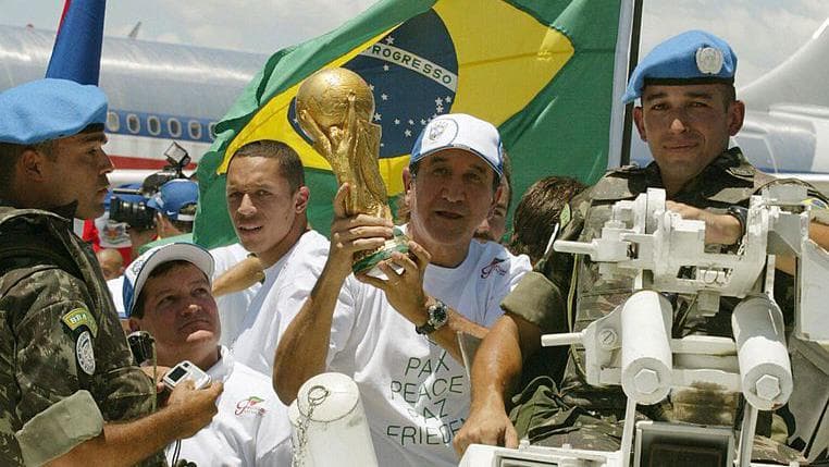 The Brazil team show off the World Cup trophy in Haiti in 2004, they are escorted by UN peacekeepers