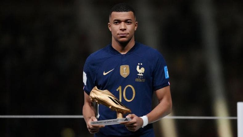 Kylian Mbappe holding the 2022 World Cup Golden Boot trophy
