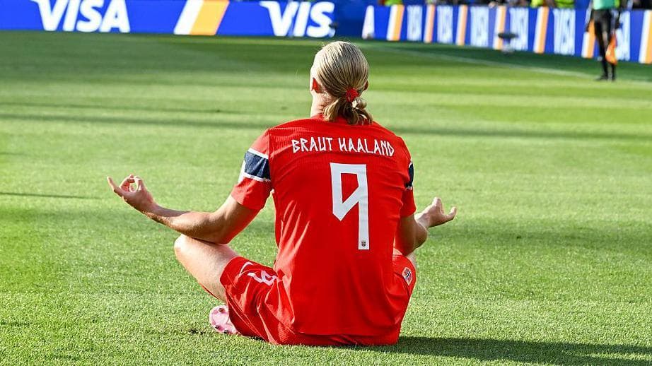 Erling Haaland sits on the grass to celebrate after scoring in the FIFA World Cup Group I match between Iraq and Norway