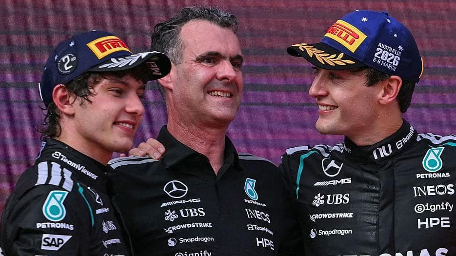 Kimi Antonelli and George Russell celebrate on the podium with Hywel Thomas, managing director of Mercedes AMG High Performance Powertrains, after F1's Australian Grand Prix in 2026